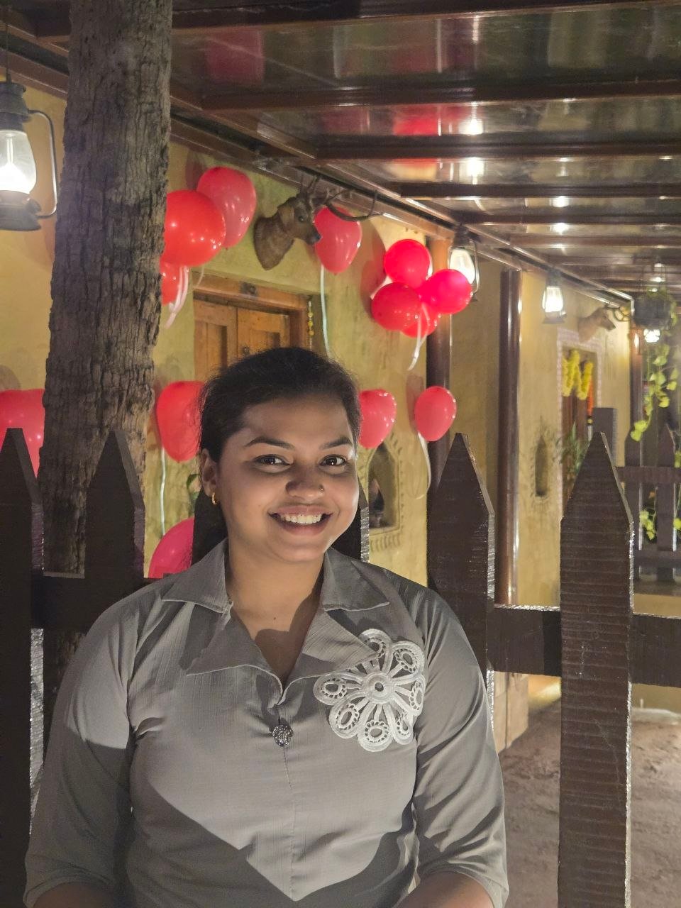 The birthday girl smiling under red balloons and lanterns